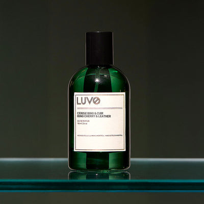 Bing Cherry & Leather eau de parfum 100ml in a refillable green glass bottle on a glass shelf